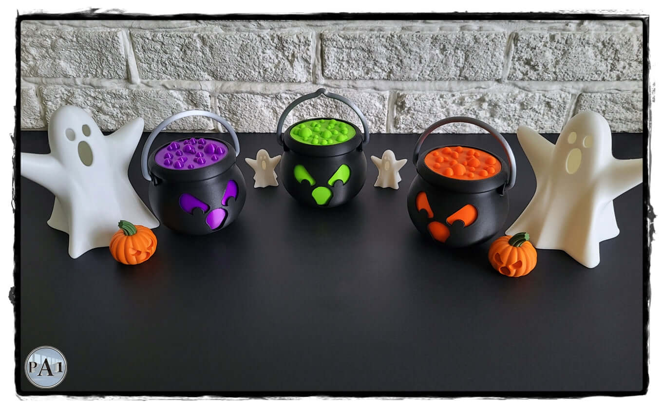 Halloween LED cauldron tea light holders with spooky ghost and pumpkin accents on a dark surface.